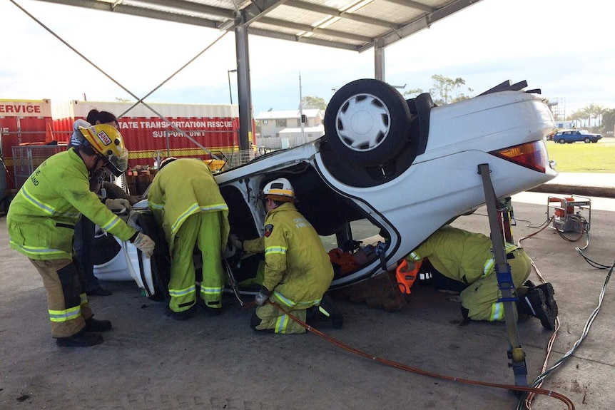 Emergency crew does exercise using Jaws of Life equipment to rescue person trapped in overturned car in Brisbane
