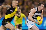 Patrick Dangerfield runs with the ball, while Dustin Martin and a few other players trail in his wake