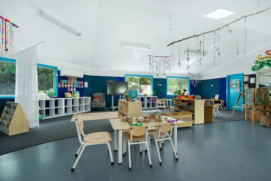 The interior room of a childcare centre with tables and bookshelves.