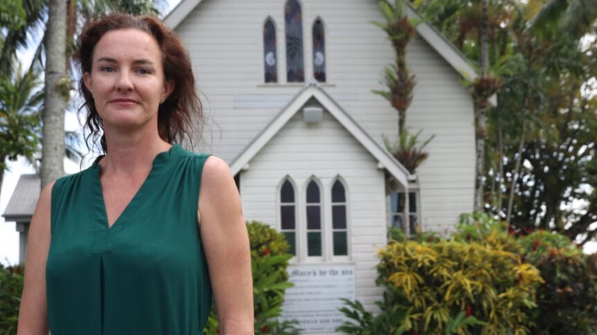 Woman stands outside St Mary's By the Sea church at Port Douglas.