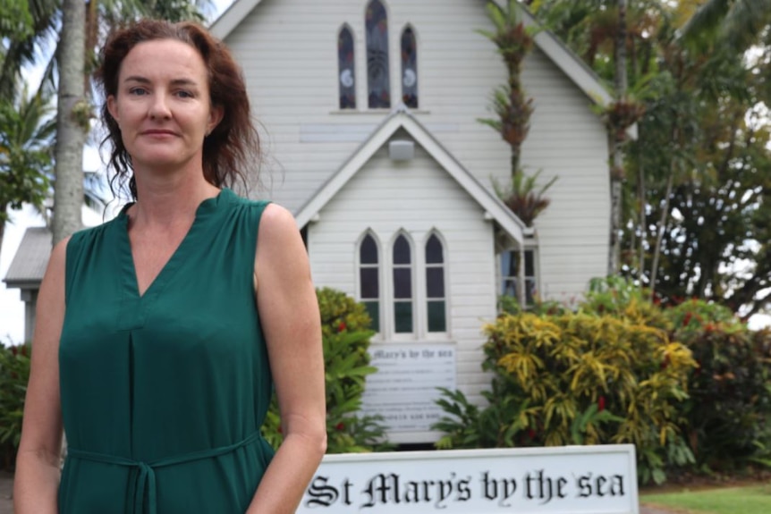 Woman stands outside St Mary's By the Sea church at Port Douglas.