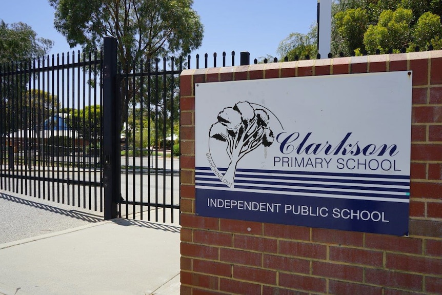 A gate and brick fence outside a school with a blue and white sign for Clarkson Primary School on the fence.