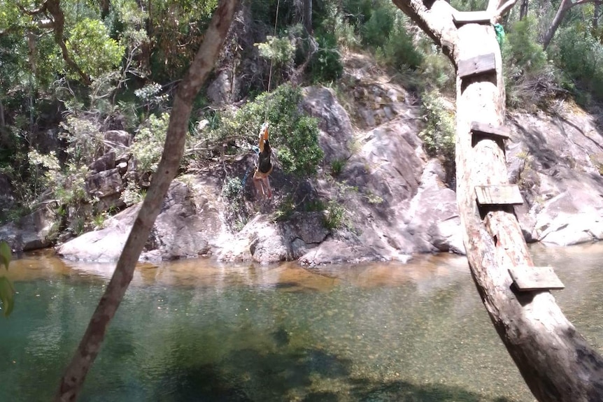 A bush swimming hole, surrounded by rocks and trees.