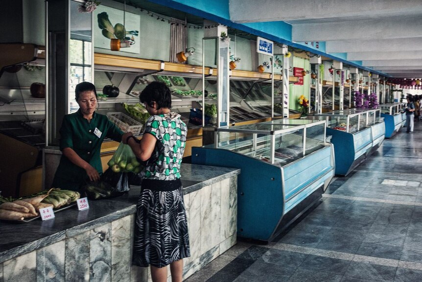A North Korean woman buys groceries from an almost empty store.