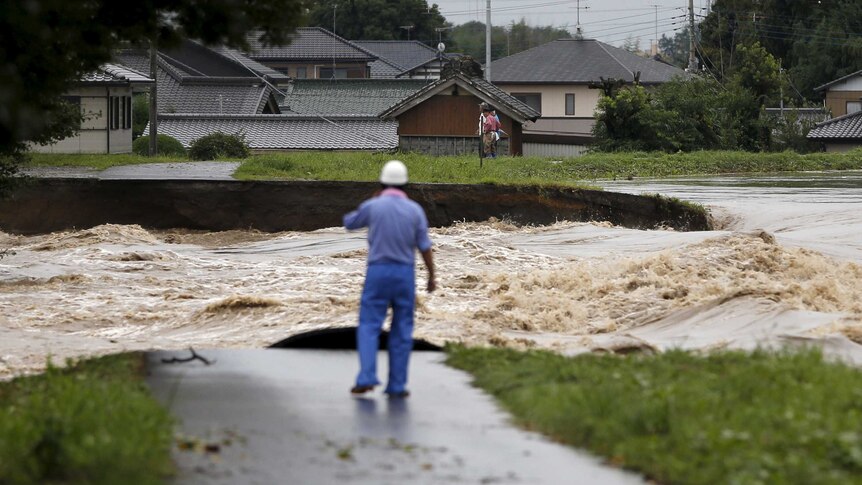 People look at flood waters from the Kinugawa river caused by Typhoon Etau