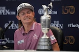 Australian golfer Cameron Smith gives a big grin as he looks at the Claret Jug, the trophy for winning The Open at St Andrews.