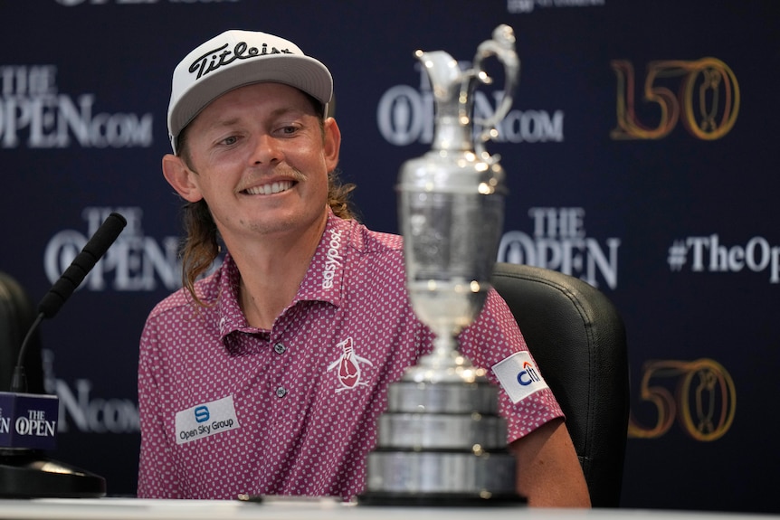 Australian golfer Cameron Smith gives a big grin as he looks at the Claret Jug, the trophy for winning The Open at St Andrews.