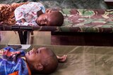 Two sick children look sad while lying on stretchers in hospital.