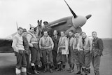 A black and white photo of a spitfire plane and pilots.