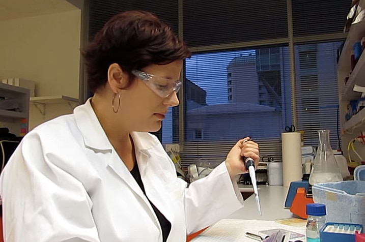 Dr Rachael Dunlop with short brown hair and white lab coat does some lab work with a pipette