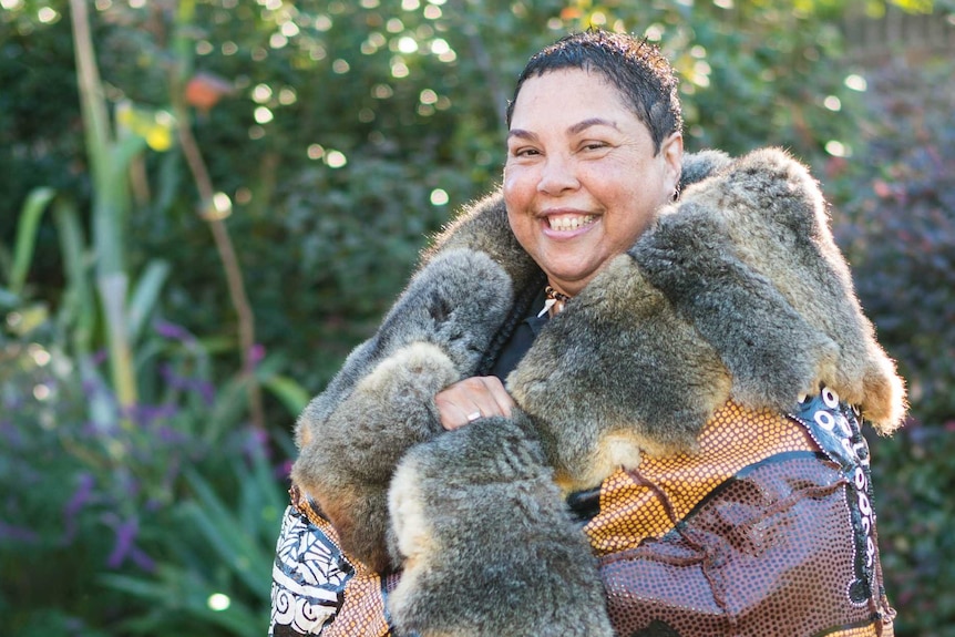 Theresa Ardler smiles with her budbili, possum skin cloak, wrapped around her.