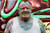 Man with colourful full body and face tattoos.