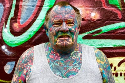 Man with colourful full body and face tattoos.
