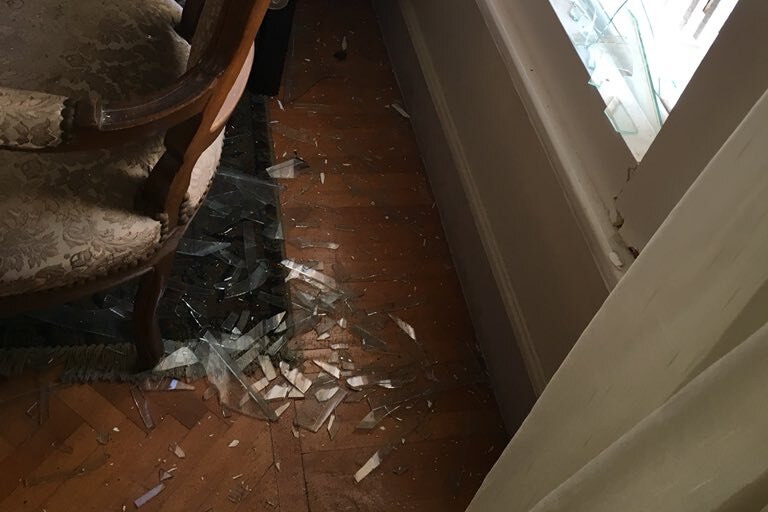 Tight shot of broken glass next to furniture on a wooden floor.