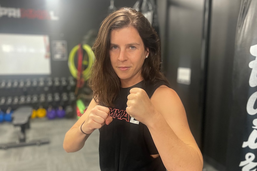 Jessie Jones is in a fighting stance with her fists in front of her inside Primal MMA. 