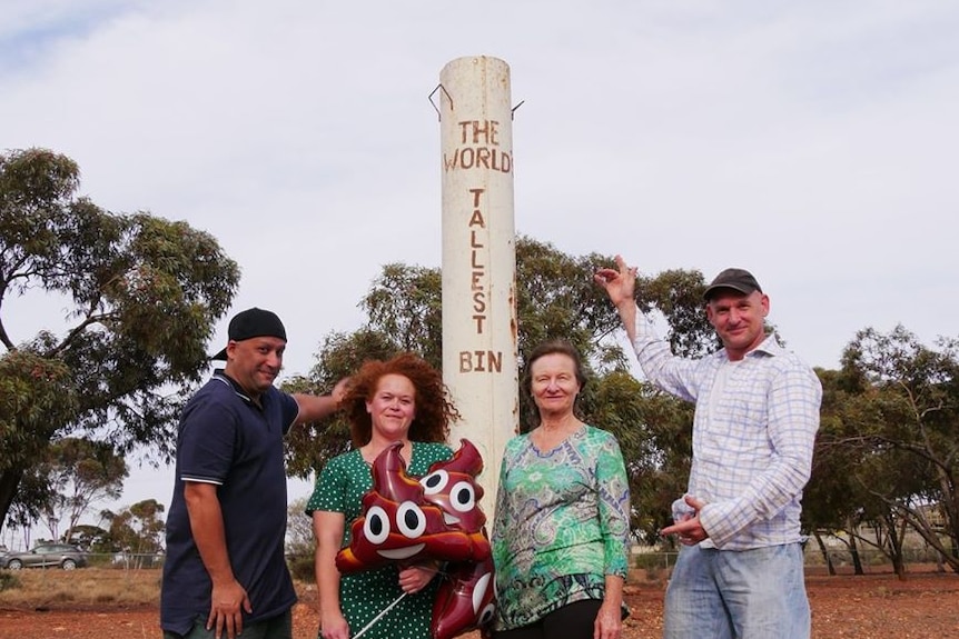 Four people stand near a structure called Kalgoorlie's World's Tallest Bin.