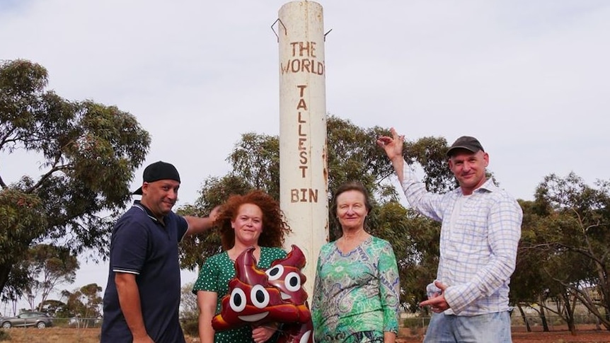 Four people stand near a structure called Kalgoorlie's World's Tallest Bin.