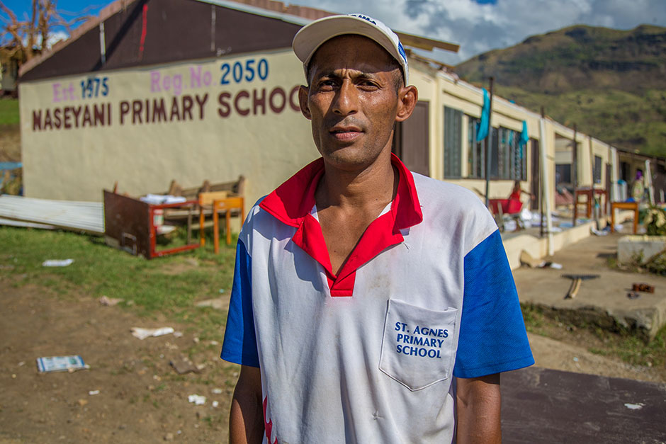 Man stands in front of cyclone-hit primary school, close to camera