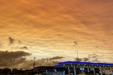 A car park in the foreground with a golden cloud blanket overhead.