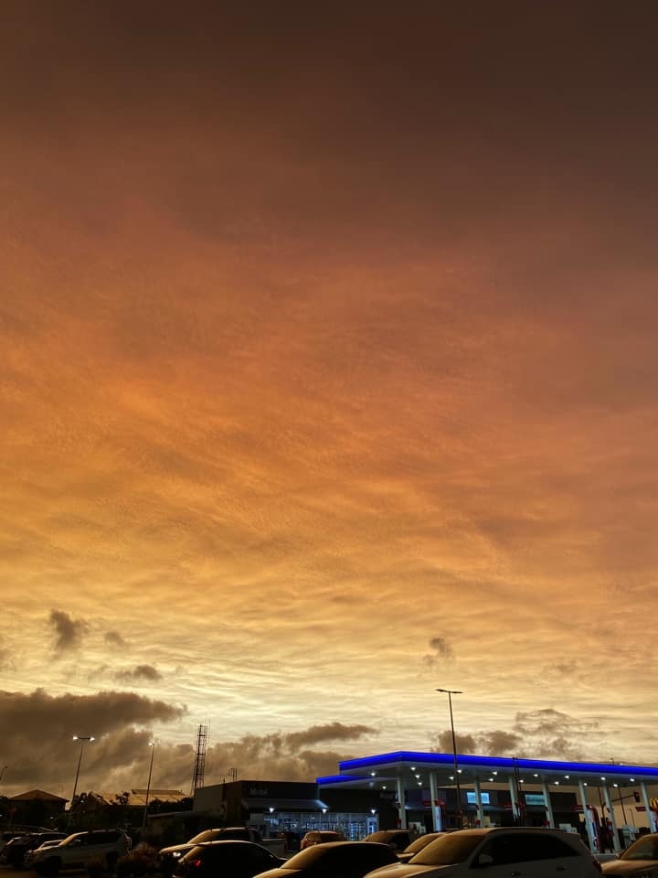 A car park in the foreground with a golden cloud blanket overhead.