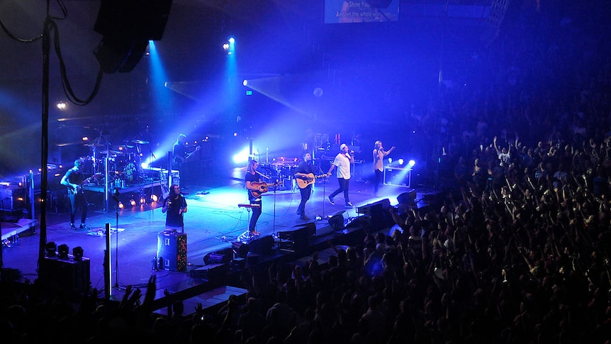 hillsong concert with musicians standing on stage with crowds of people below