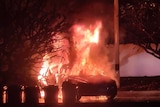 Car engulfed in flames on street. 