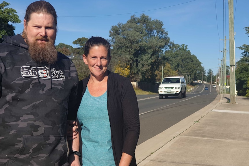 A man and woman stand in front of a road.