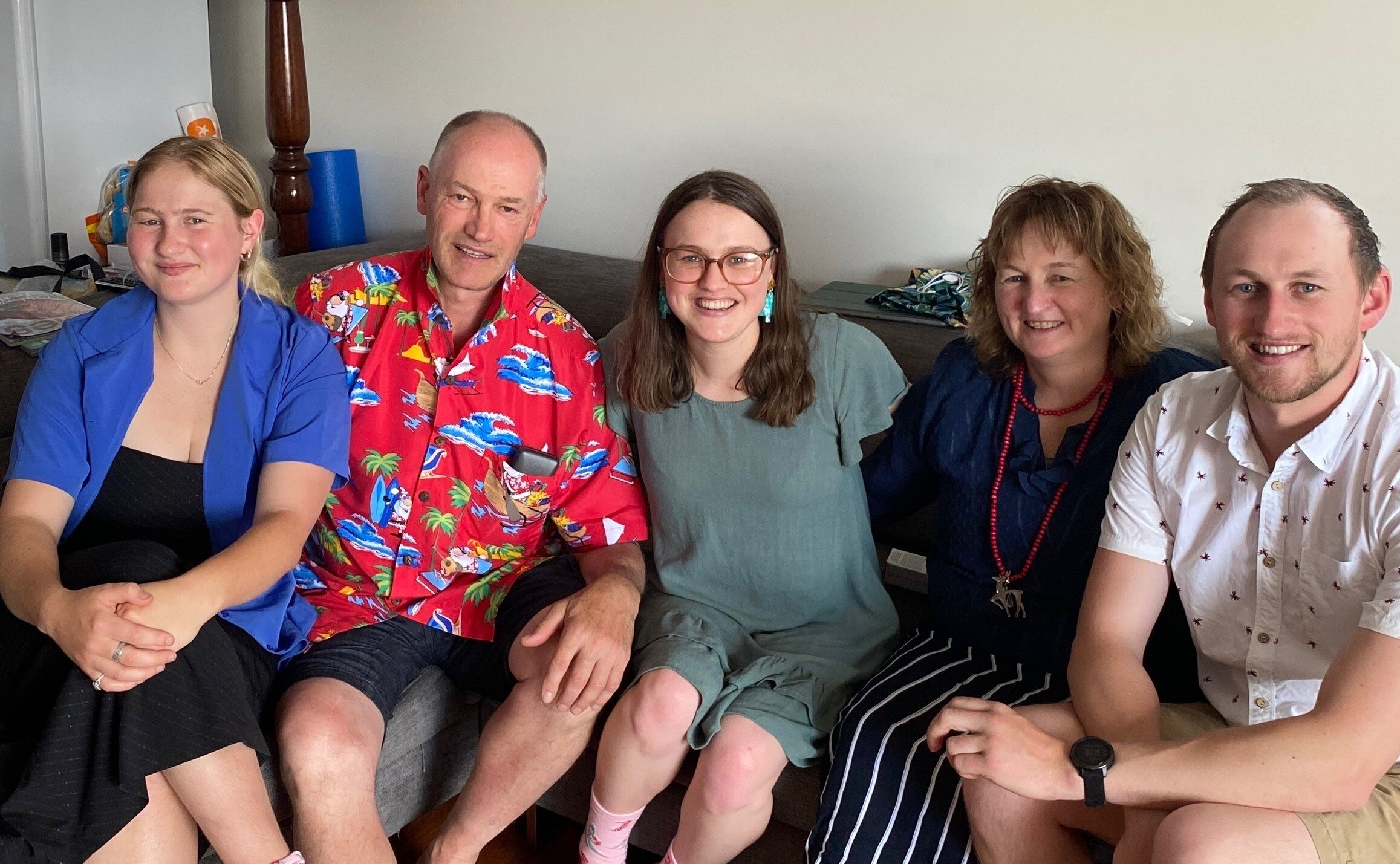 A family of five sitting together on a couch.