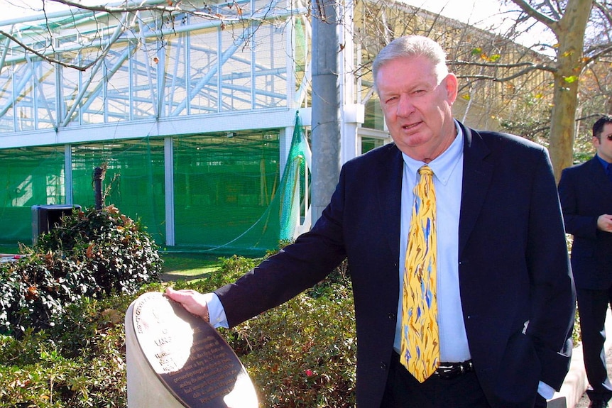 Graeme Langlands stands next to a plaque