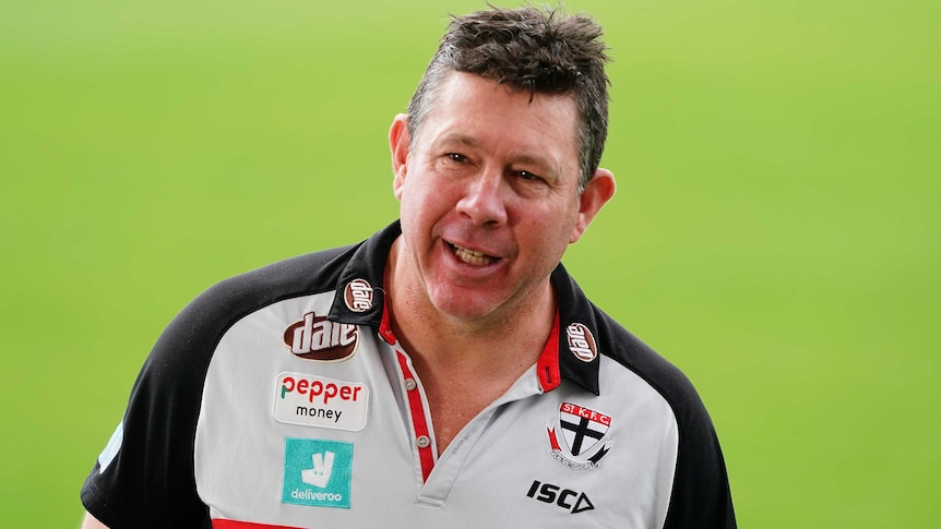 An AFL coach smiles before the game.