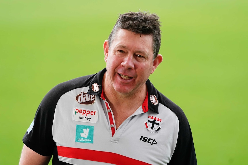 An AFL coach smiles before the game.