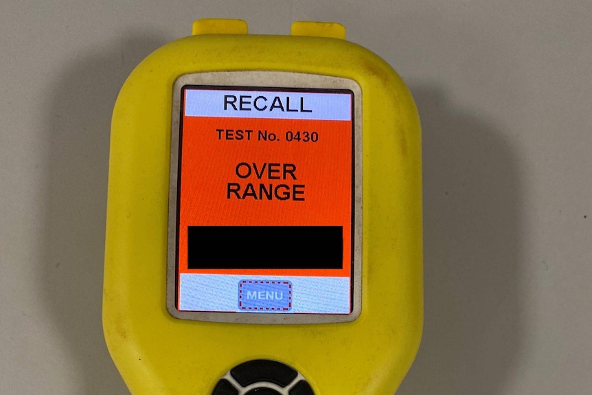 A yellow alcohol breath test machine that has a red sign saying "over range"