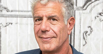 A man with grey hair and a subtle smile looks towards the camera.