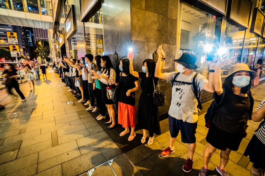 A group of people holding hands in front of a building.