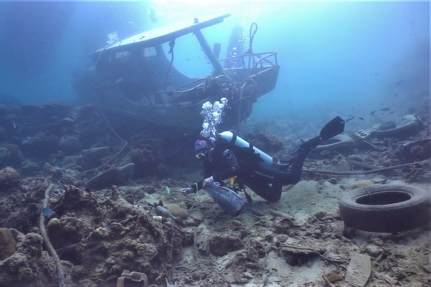 A woman diving picking up rubbish from the bed of the ocean