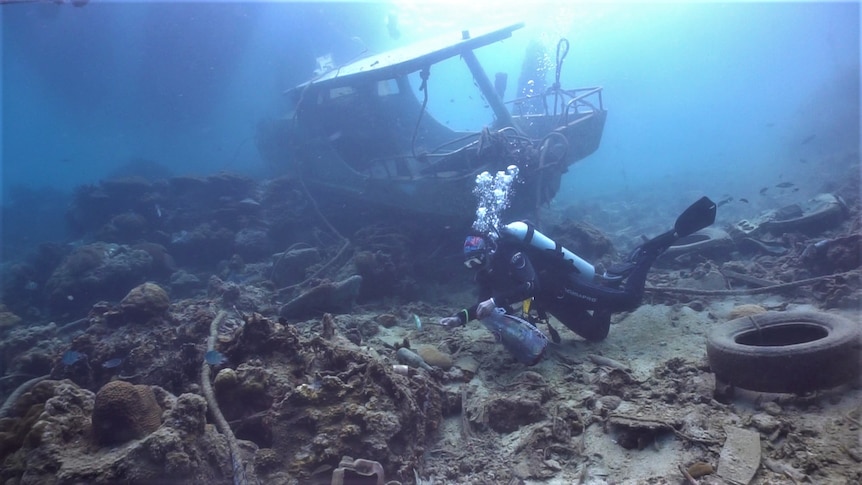 A woman diving picking up rubbish from the bed of the ocean