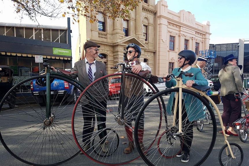 Three people standing next to penny-farthing bicycles in Ballarat.