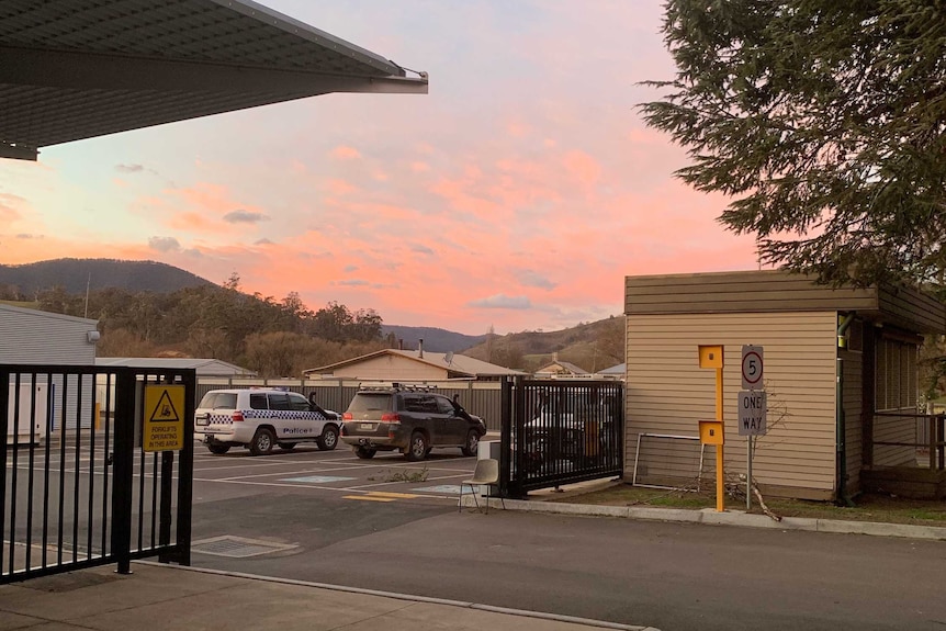 Emergency services four-wheel drives sit in a carpark under a pink sunrise sky.