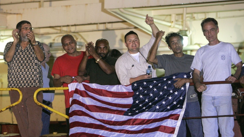 Crew members of Maersk Alabama hold the US flag
