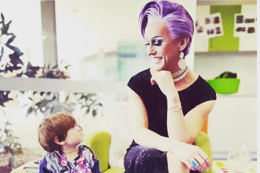 drag performer cougar morrison looking down at a small child smiling