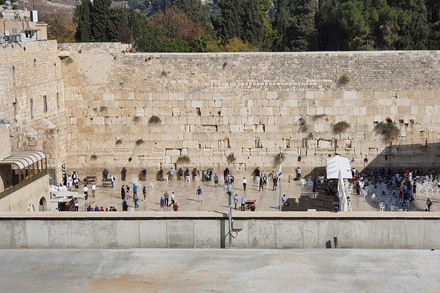 A group of people lining up and facing a big wall
