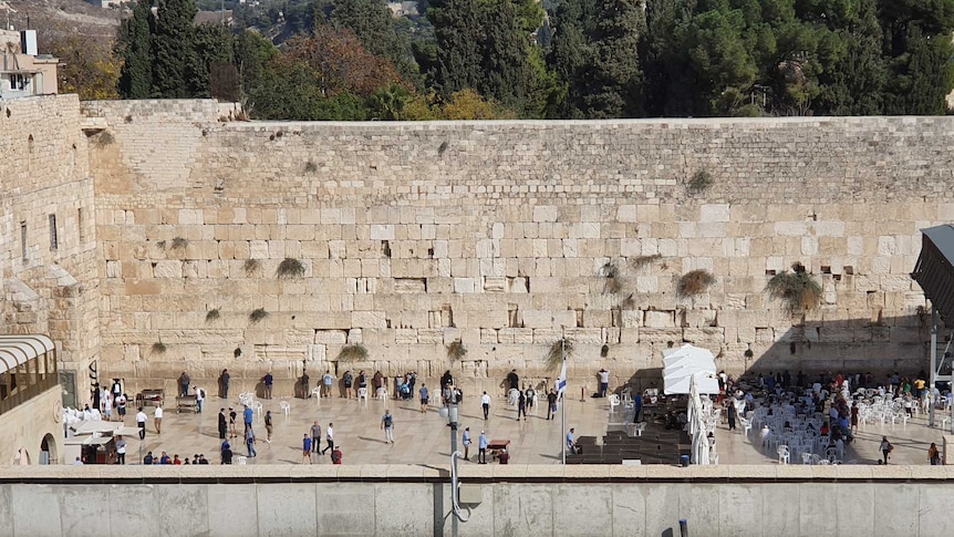 A group of people lining up and facing a big wall