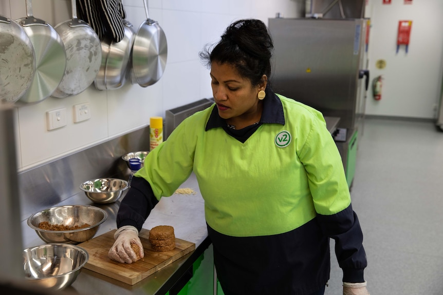 A woman forms plant-based burger patties on a kitchen bench.