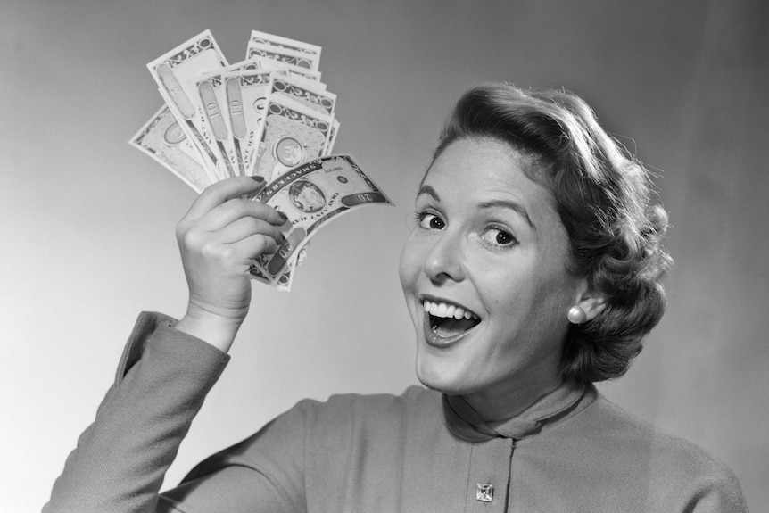 Black and white image of a woman smiling and holding a wad of cash.