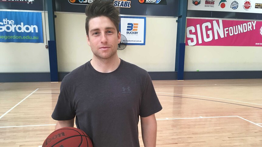 Braiden Fitzsimmons standing on an empty basketball court holding a basketball