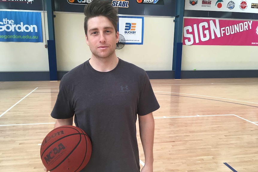 Braiden Fitzsimmons standing on an empty basketball court holding a basketball