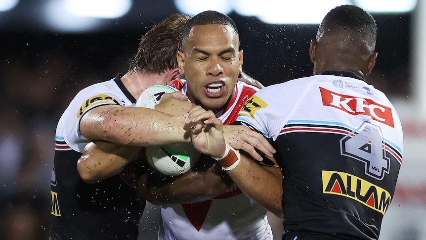 A St Helens player is tackled by two Penrith Panthers players during the World Club Challenge.