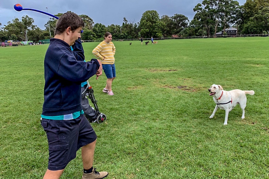 Matthieu Piggott preparing to throw a tennis ball to a very excited-looking dog.