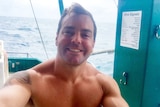 Ruben McDornan smiles shirtless on a boat after a dive.