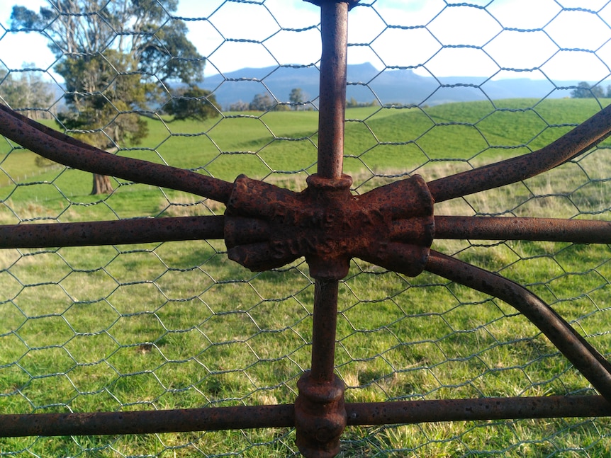 A rusty centre piece of a gate, the words 'sunshine mckay' are just visible 